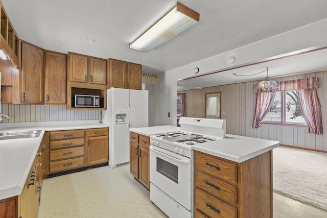 kitchen featuring pendant lighting, sink, white appliances, and a kitchen island