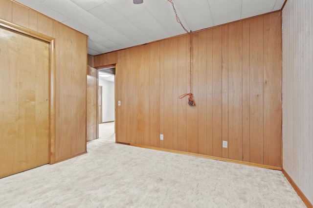 unfurnished bedroom featuring light colored carpet and wooden walls