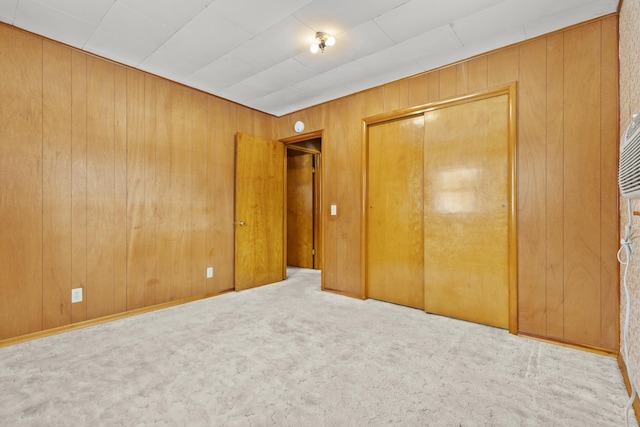 unfurnished bedroom with wooden walls, carpet flooring, and a closet