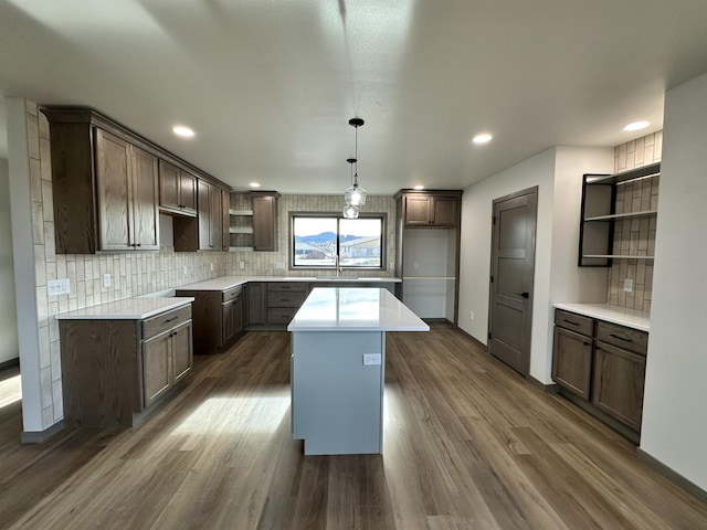 kitchen featuring backsplash, decorative light fixtures, dark hardwood / wood-style floors, and a kitchen island