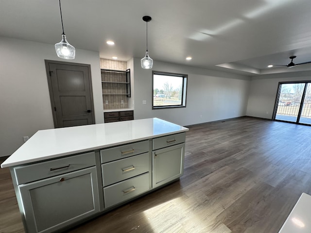 kitchen with decorative light fixtures, dark hardwood / wood-style floors, a raised ceiling, and a kitchen island