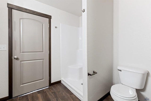 bathroom with hardwood / wood-style flooring, a shower, and toilet