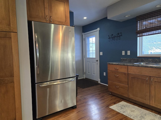 kitchen with sink, stainless steel fridge, dark hardwood / wood-style floors, and dark stone counters