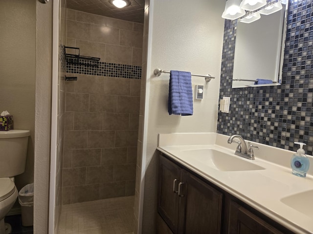 bathroom featuring vanity, tasteful backsplash, toilet, and tiled shower