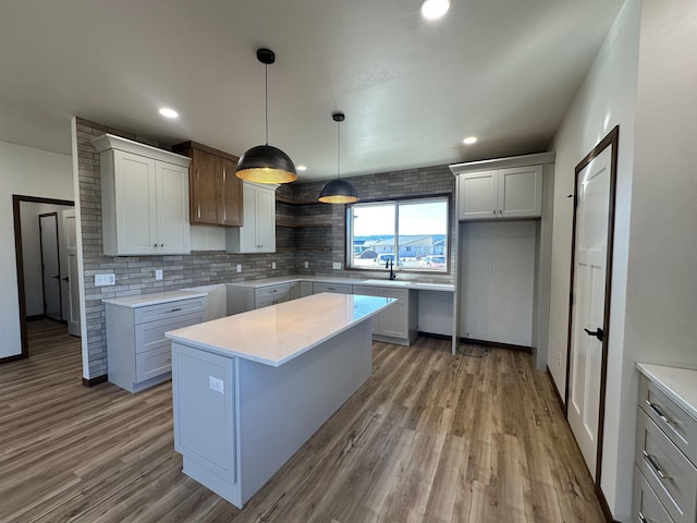 kitchen featuring hanging light fixtures, backsplash, hardwood / wood-style floors, and a center island