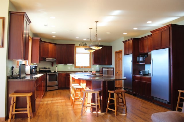 kitchen featuring dark countertops, appliances with stainless steel finishes, and a kitchen bar