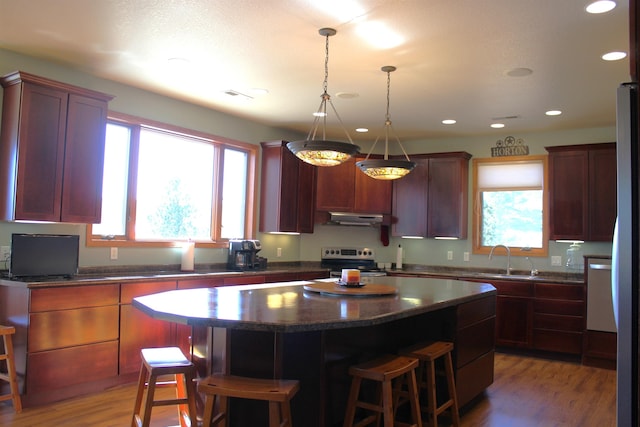 kitchen with light wood-type flooring, stainless steel electric range, a breakfast bar, and a center island