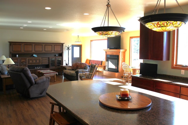 dining room featuring a glass covered fireplace, recessed lighting, and dark wood-style floors