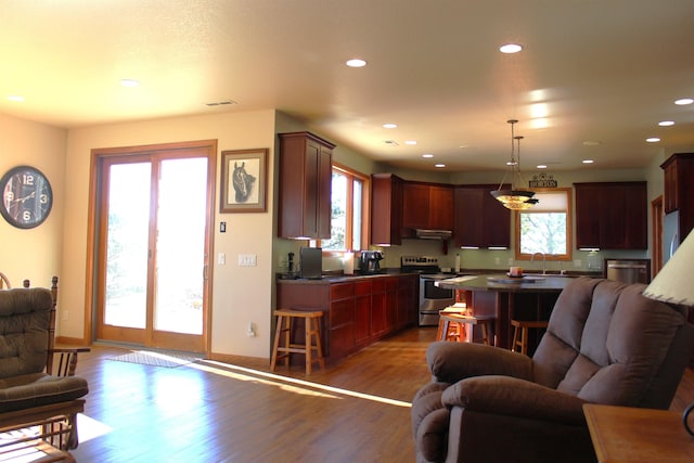 kitchen with dark countertops, open floor plan, recessed lighting, stainless steel electric range, and wood finished floors