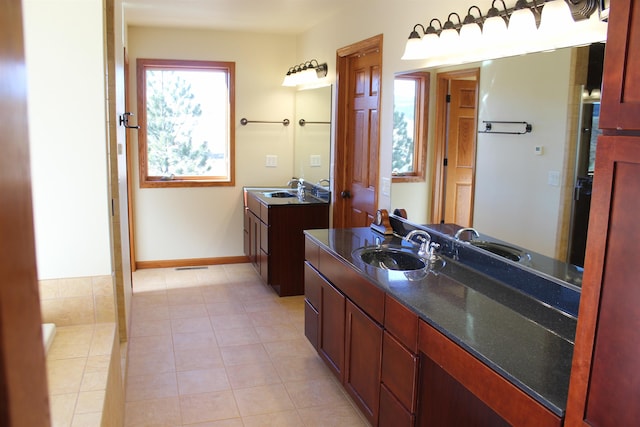 bathroom featuring a sink, baseboards, two vanities, and tile patterned flooring