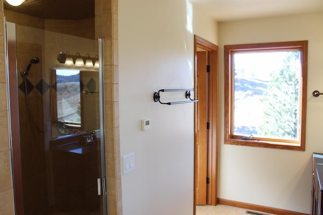 full bath featuring tile patterned floors, baseboards, a stall shower, and vanity