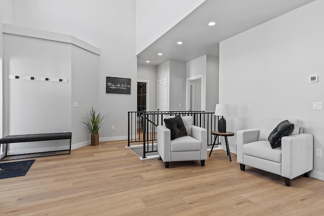 living area featuring light hardwood / wood-style floors and a high ceiling