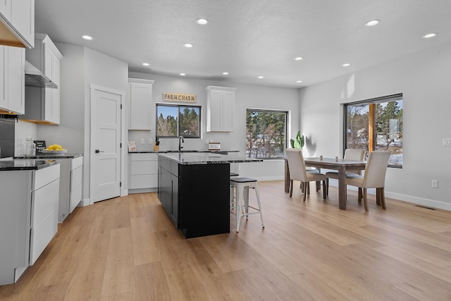 kitchen with a center island, white cabinets, and light wood-type flooring