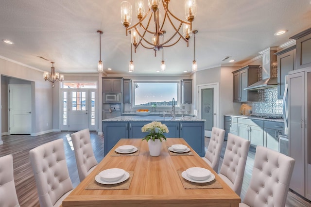 dining area featuring crown molding, wood-type flooring, sink, and a notable chandelier