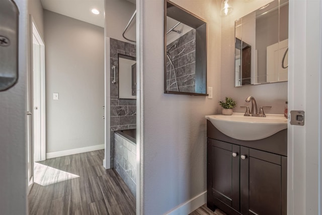 bathroom with hardwood / wood-style flooring, vanity, and tub / shower combination