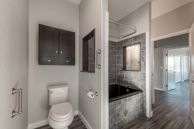 bathroom featuring tiled shower / bath, wood-type flooring, and toilet