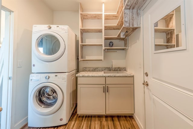 clothes washing area featuring sink, light wood-type flooring, cabinets, and stacked washer / dryer