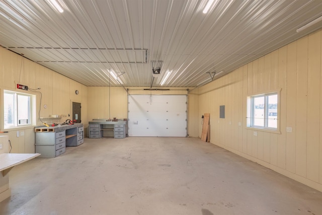 garage with a garage door opener, electric panel, and a workshop area