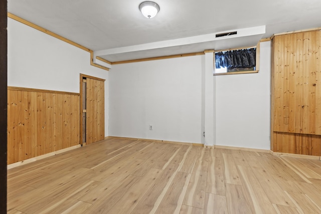 basement with wooden walls and light hardwood / wood-style flooring