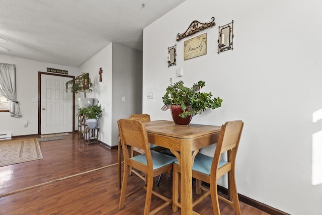 dining room with a baseboard radiator, dark wood-type flooring, and a textured ceiling