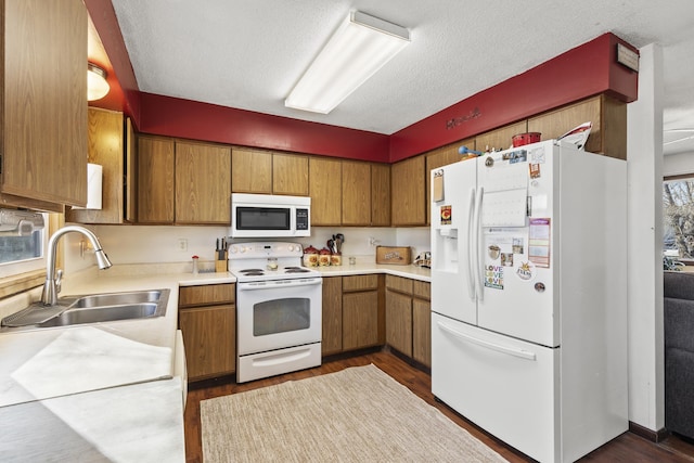 kitchen with white appliances, dark hardwood / wood-style flooring, sink, and a textured ceiling