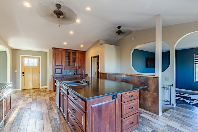 kitchen with lofted ceiling, sink, a kitchen island with sink, ceiling fan, and light hardwood / wood-style floors