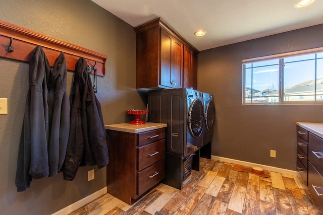 laundry room featuring cabinets, separate washer and dryer, and light hardwood / wood-style flooring