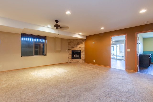 unfurnished living room with a stone fireplace, carpet flooring, and ceiling fan