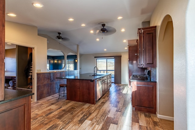 kitchen with dark hardwood / wood-style floors, dishwasher, sink, a kitchen breakfast bar, and a kitchen island with sink