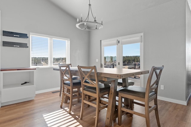 dining room featuring lofted ceiling, a wealth of natural light, light hardwood / wood-style floors, and a notable chandelier