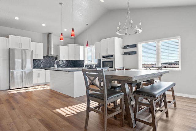 kitchen with white cabinetry, wall chimney range hood, a center island, and appliances with stainless steel finishes