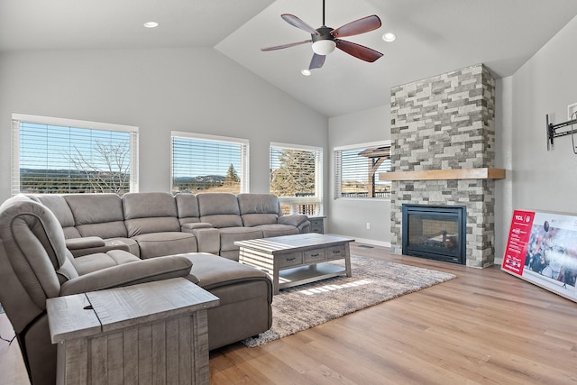 living room with a fireplace, high vaulted ceiling, ceiling fan, and light wood-type flooring