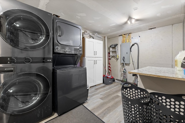 clothes washing area featuring stacked washing maching and dryer and light hardwood / wood-style floors