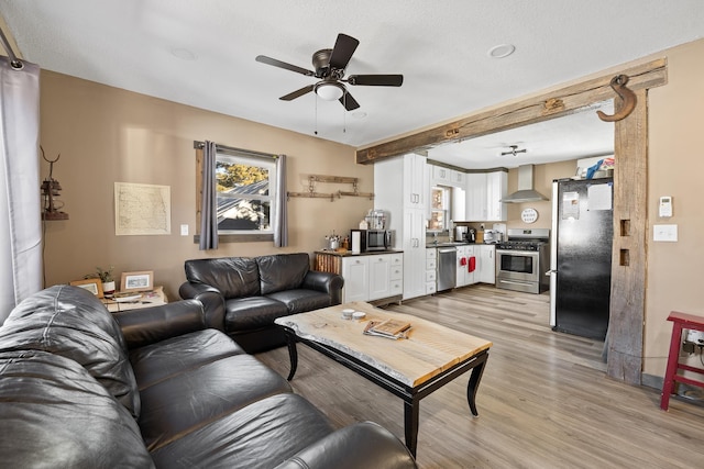 living room featuring a textured ceiling, ceiling fan, and light hardwood / wood-style flooring