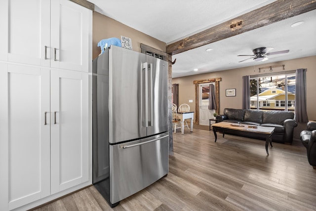 kitchen with light hardwood / wood-style flooring, stainless steel fridge, beamed ceiling, and white cabinets