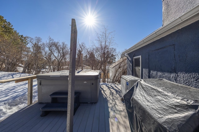 snow covered deck with a hot tub