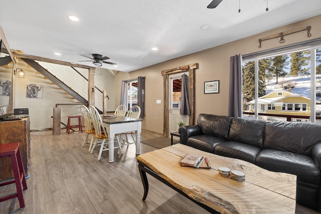 living room with ceiling fan, a textured ceiling, and light wood-type flooring