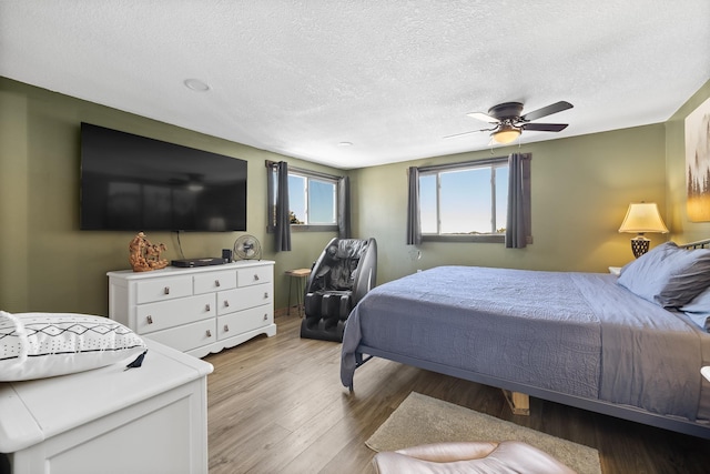 bedroom with ceiling fan, light hardwood / wood-style floors, and a textured ceiling