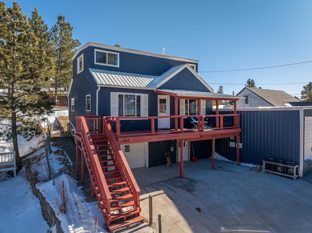 snow covered rear of property with a garage and a wooden deck