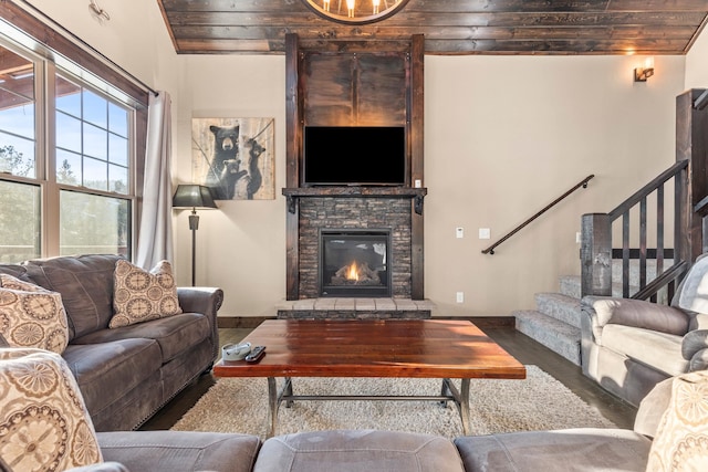 living room featuring hardwood / wood-style flooring, a stone fireplace, and wooden ceiling