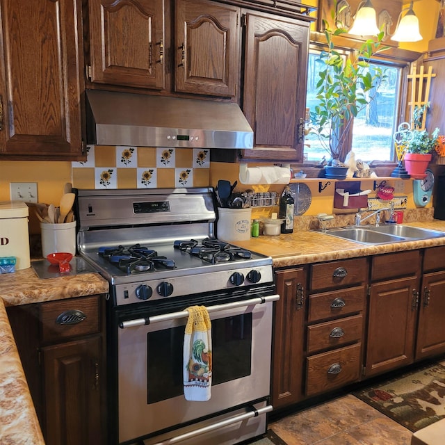 kitchen featuring sink, stainless steel gas range, dark brown cabinets, ventilation hood, and decorative light fixtures