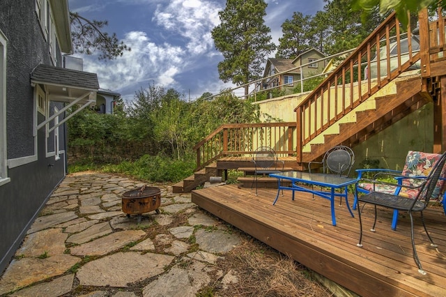 wooden terrace with a fire pit and a patio