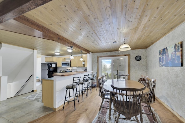 dining area featuring beamed ceiling, wooden ceiling, and light wood-type flooring