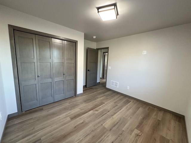 unfurnished bedroom featuring light hardwood / wood-style floors and a closet