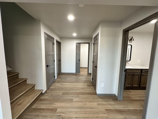 corridor with sink and light wood-type flooring