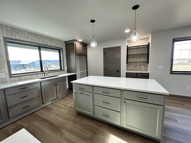 kitchen featuring sink, hanging light fixtures, dark hardwood / wood-style floors, a kitchen island, and backsplash