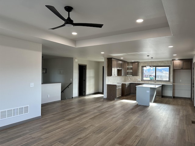 kitchen featuring pendant lighting, backsplash, dark hardwood / wood-style flooring, a center island, and dark brown cabinets