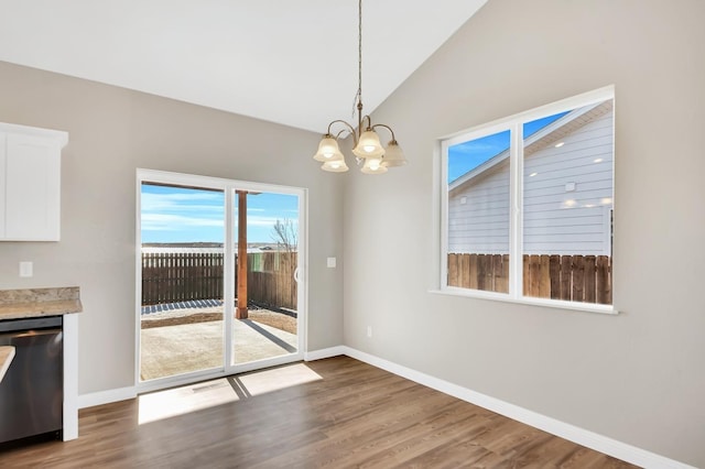 unfurnished dining area featuring lofted ceiling, a notable chandelier, baseboards, and wood finished floors