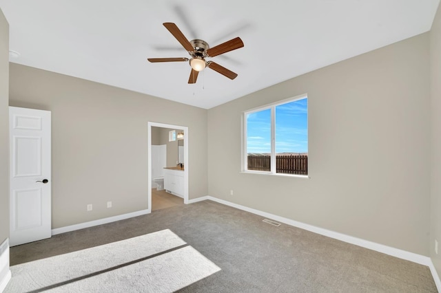 unfurnished bedroom with baseboards, visible vents, a ceiling fan, ensuite bath, and carpet flooring