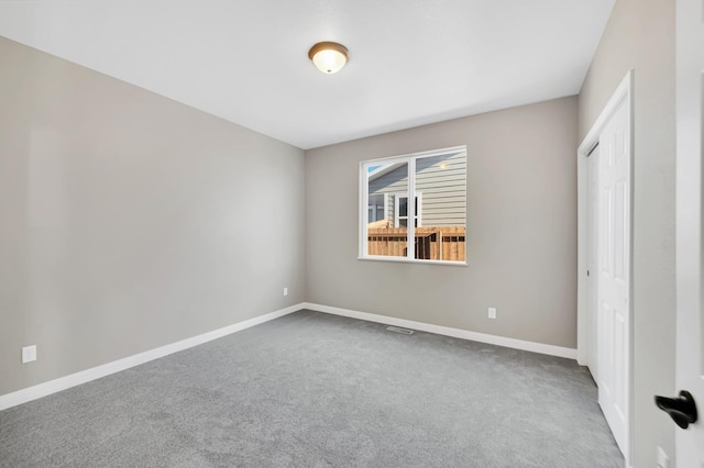 carpeted empty room featuring visible vents and baseboards